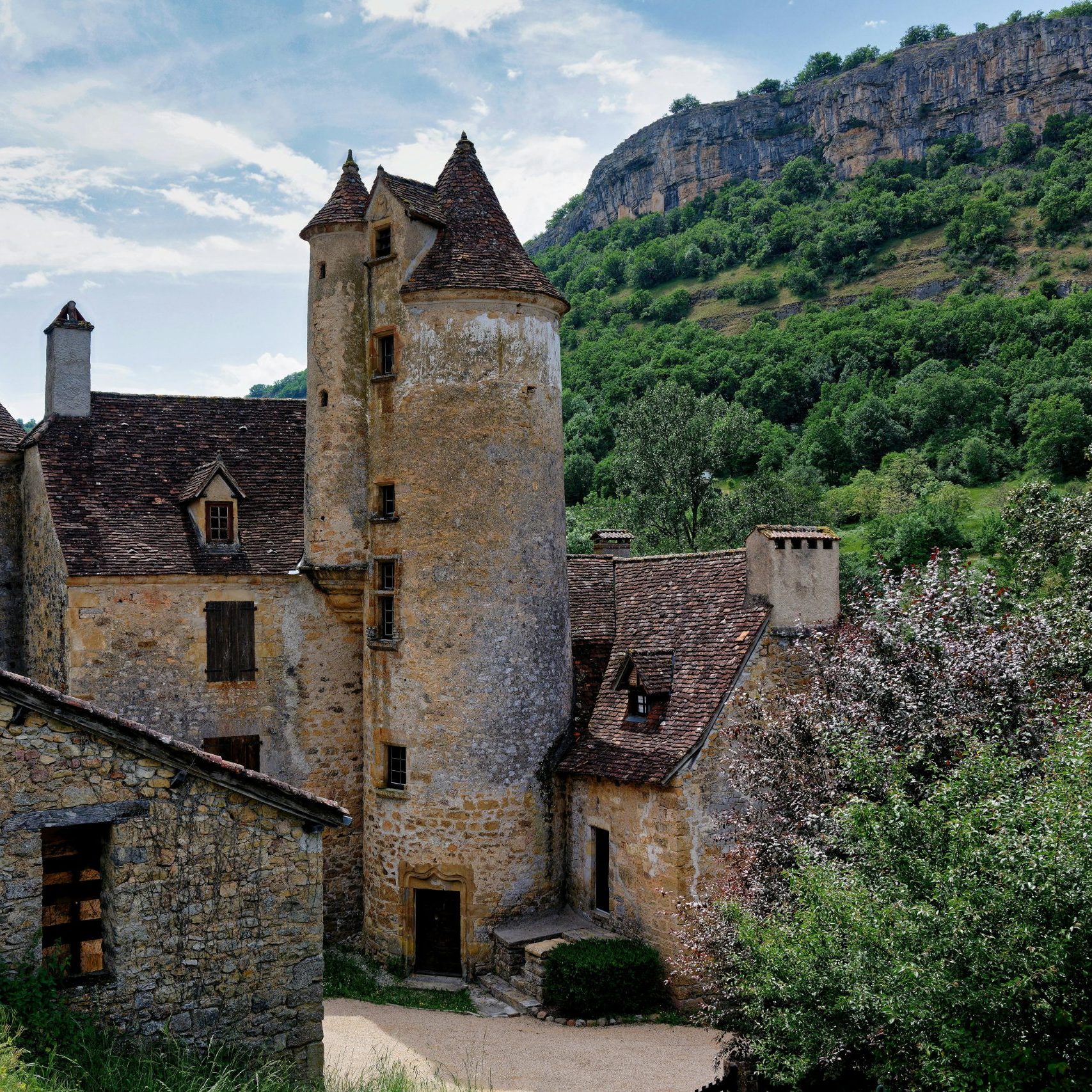 A stunning medieval chateau in Autoire, Occitanie surrounded by lush greenery.
