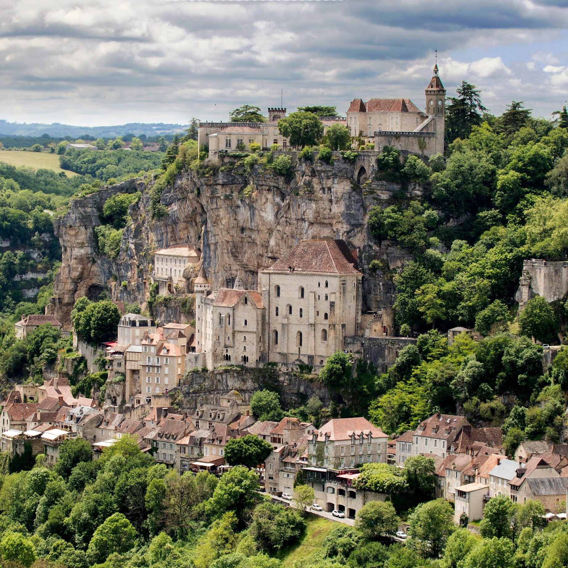 Capture of the historic cliffside village of Rocamadour, nestled in lush greenery.
